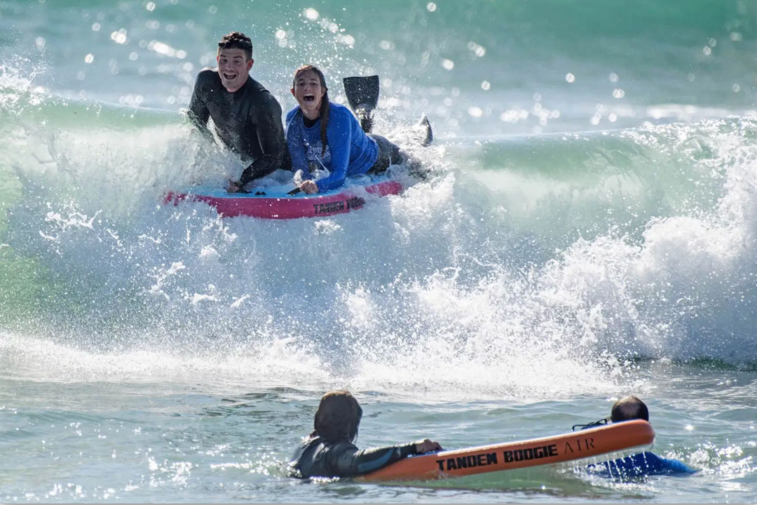 Ambassadors for San Clemente based Tandem Boogie demonstrate the company’s tandem boogie board, which will make an appearance on an upcoming episode of Shark Tank, as they ride a wave side-by-side at T-Street Beach on Friday, March 5, 2021. (Photo by Jeff Antenore, Contributing Photographer)